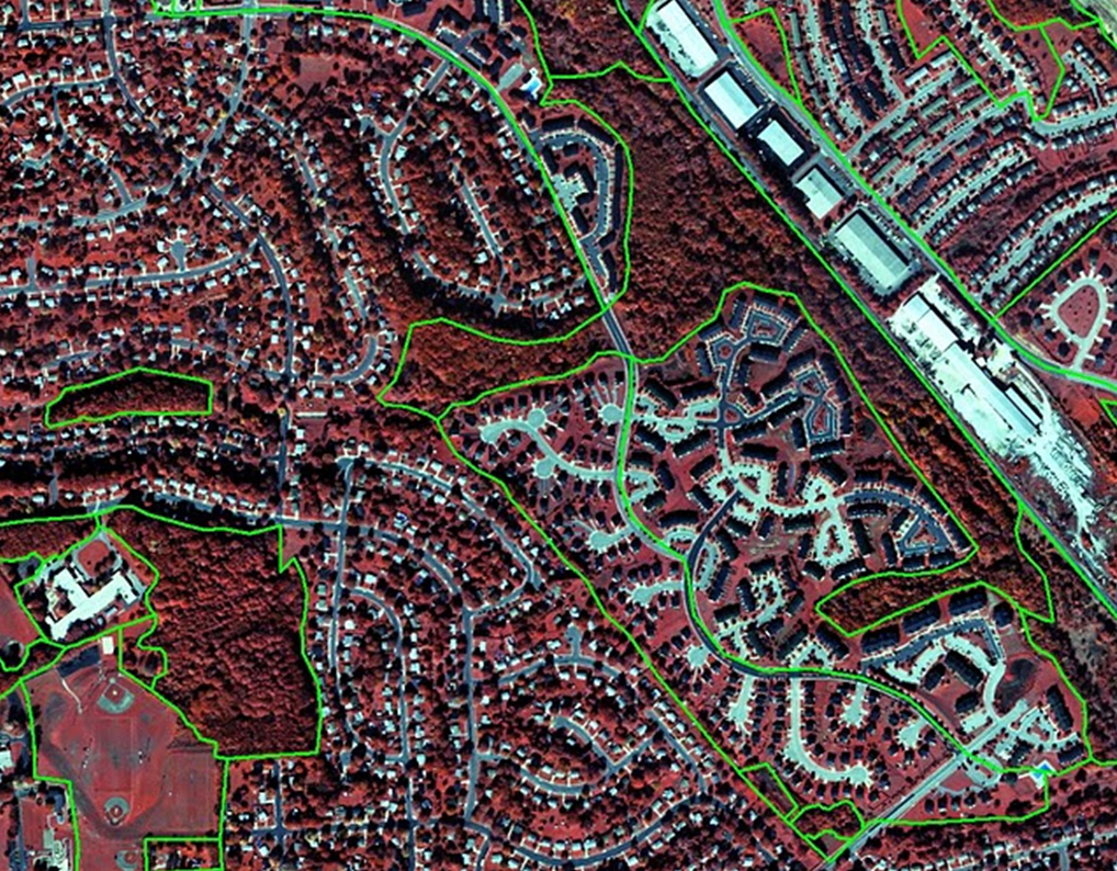 Urban spatial patchiness as represented by the HERCULES land cover classification. Urban areas include much fine-scale heterogeneity, which may be important for how the system functions socially and ecologically. In particular, spatial patchiness may control the effects of social processes and built covers on ecosystem functions. This false color infrared aerial photo of the Glyndon area of Baltimore County, MD, shows healthy vegetation in red. Impervious surfaces such as roofs, streets and parking lots, show up as other colors and can be distinguished by a computer algorithm or a human investigator. The patches in this image are differentiated on the basis of how much cover is contributed by trees, by grass, by pavement, by bare ground, and by buildings of different types. Even patches that would be classified as residential by the traditional classification differ based on several of the major contrasts in cover.