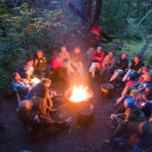 group of people sitting at a campfire