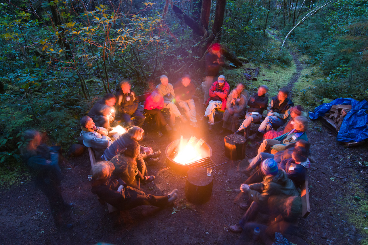 group of people sitting at a campfire