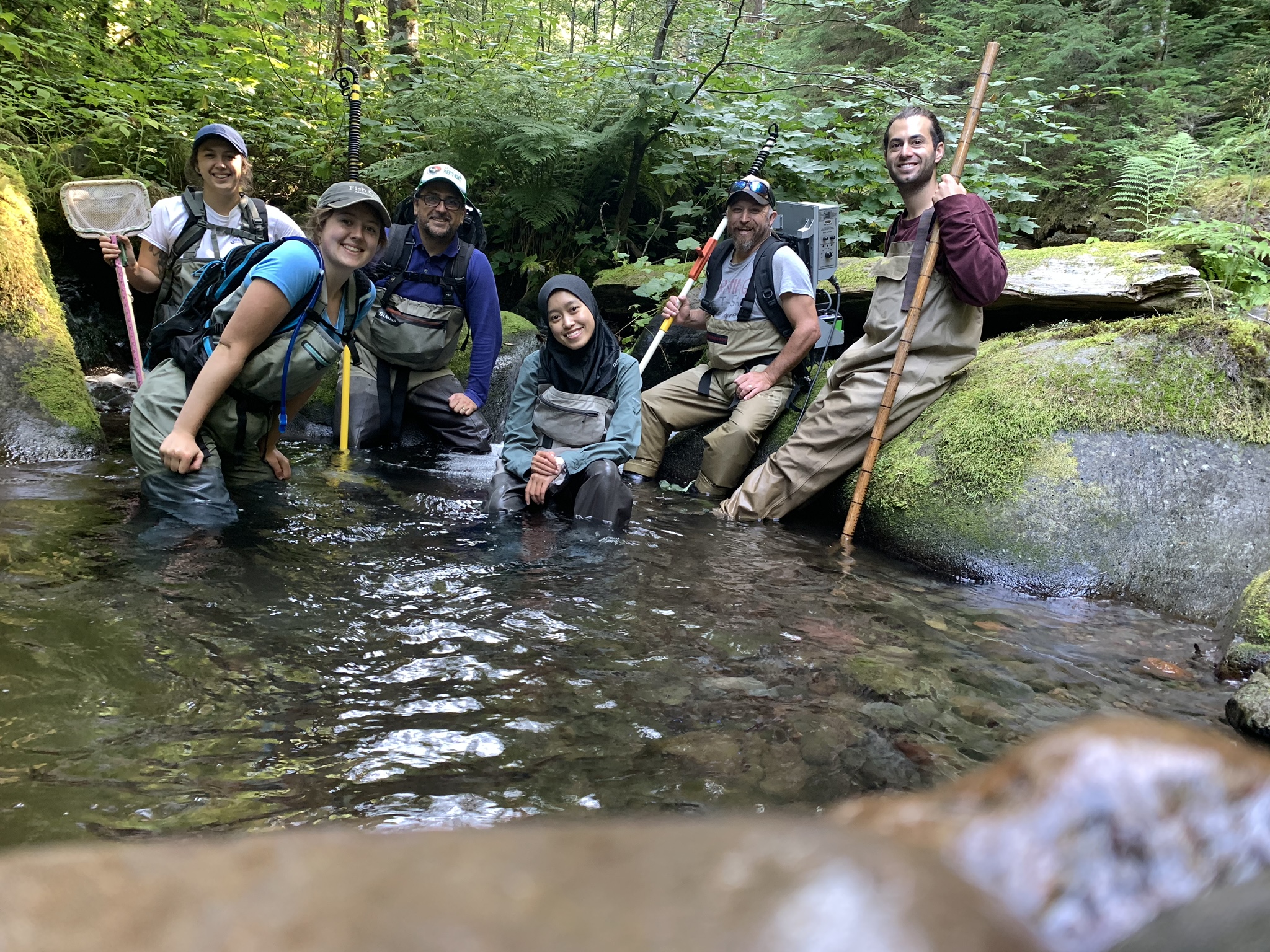 smiling group photo of adults in waders and stream sampling gear