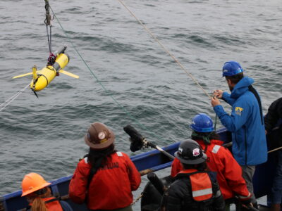 An oceanographic glider being deployed into the sea from the ship