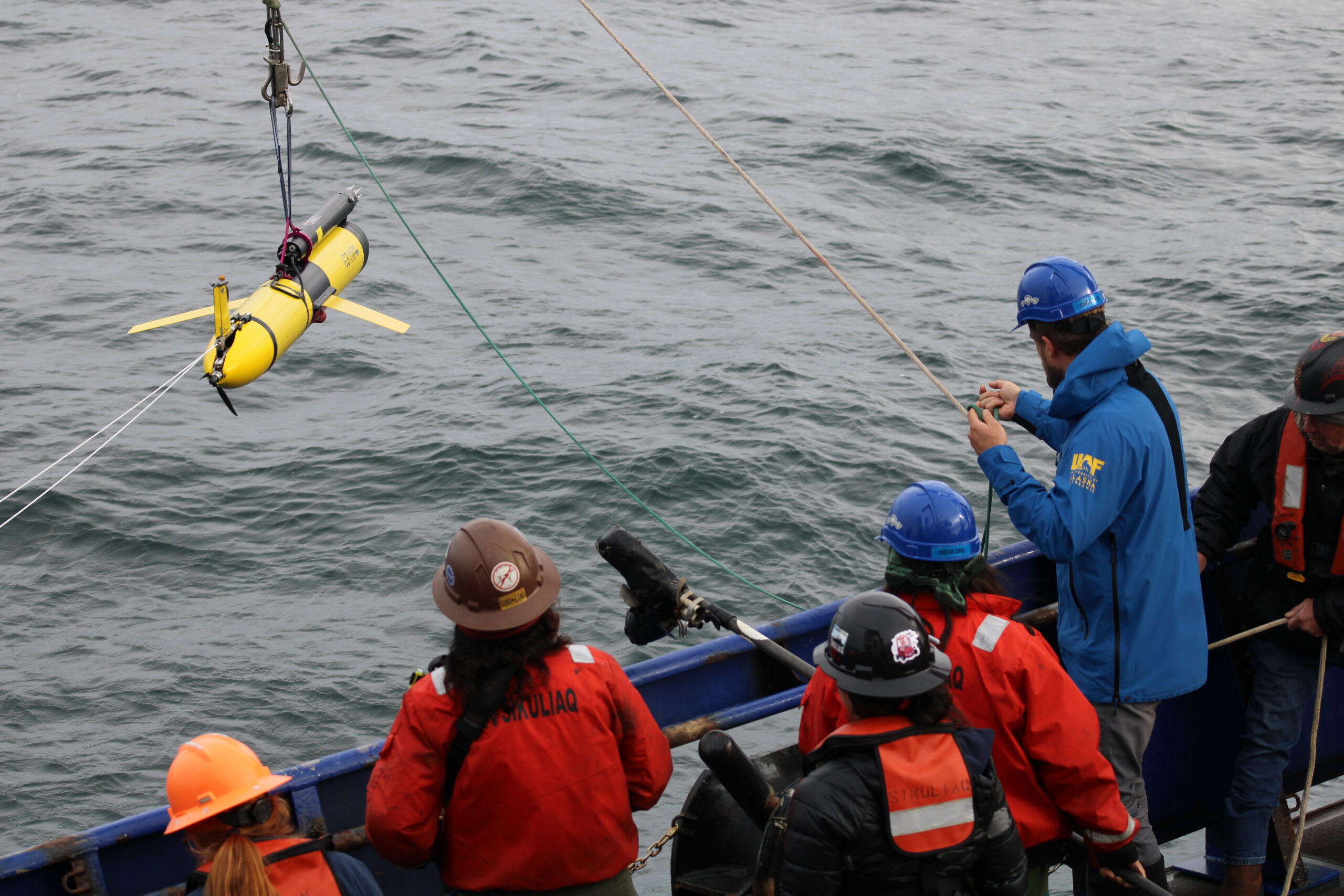 An oceanographic glider being deployed into the sea from the ship