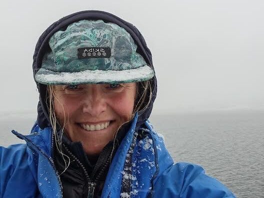 smiling, snow-covered woman in outdoor gear