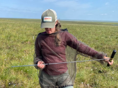 woman, with a t-handled probe in both hands.