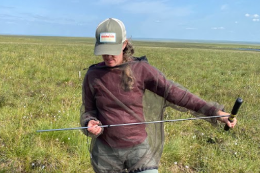 woman, with a t-handled probe in both hands.