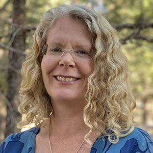 headshot of Michelle Mack with forest background