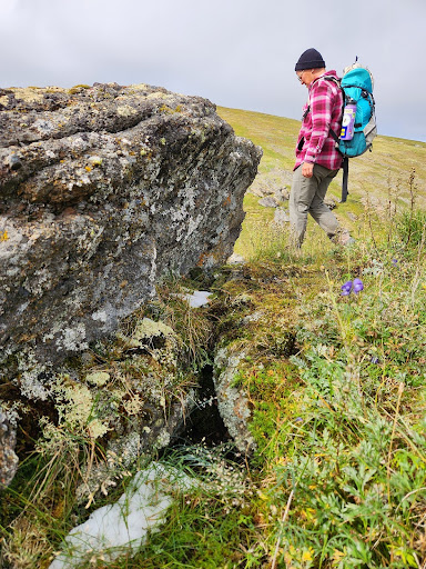 woman with large pack and beanie, skirting a rock outcrop